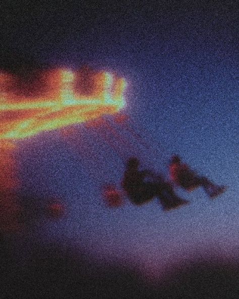 Soft silhouettes on a swing ride beneath glowing lights at twilight.